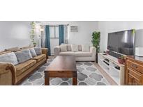 Living room with sofa, coffee table, and large TV at 381 S Ames St # B103, Lakewood, CO 80226