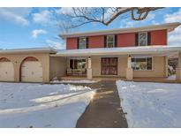 Two-story home with red siding, covered porch, and attached two-car garage, snow on the ground at 9620 E Grand Ave, Greenwood Village, CO 80111