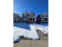 Two-story house with gray siding, snow-covered lawn, and attached garage at 5046 Espana Way, Denver, CO 80249