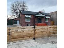 Brick ranch home with striped awnings and a new wood fence at 1453 Chester St, Aurora, CO 80010