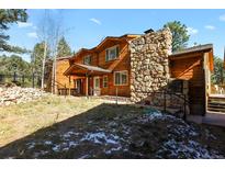 Two-story home with wood siding, stone fireplace, and deck at 28730 Mountain View Rd, Conifer, CO 80433
