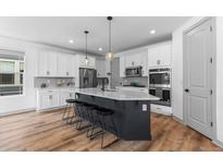 Modern kitchen with white cabinets, large island, and stainless steel appliances at 6251 Saddlesmith St, Castle Pines, CO 80108