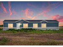 Ranch style home with blue exterior, and landscaped yard at 165 S County Road 197, Byers, CO 80103
