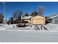 Ranch style home with attached garage and snow-covered yard at 15503 E Princeton Ave, Aurora, CO 80013