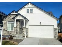Modern two-story house with a white exterior, stone accents, and a large driveway at 16487 E 111Th Pl, Commerce City, CO 80022
