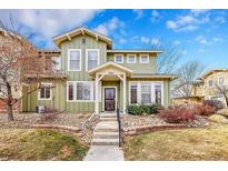 Two-story light green house with landscaping and a stone walkway at 10411 Truckee St # C, Commerce City, CO 80022