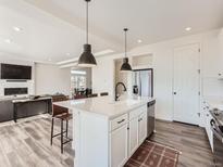 Modern kitchen with white cabinets, island, and hardwood floors at 4197 N Rome St, Aurora, CO 80019