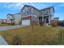 Two-story house with gray siding and brick accents, and a two-car garage at 13644 Ulster St, Thornton, CO 80602