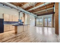 Open concept kitchen with island, wood floors and exposed ductwork at 2955 Inca St # 2N, Denver, CO 80202