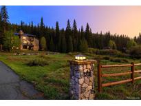 House exterior at dusk, nestled in a wooded mountain setting at 1920 Tiger Rd, Breckenridge, CO 80424