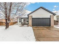 Ranch style home with attached garage and snow covered front yard at 2206 E 97Th Ave, Thornton, CO 80229