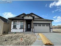 New construction home with light beige siding, dark brown accents, and a two-car garage at 152 Limbach Ct, Monument, CO 80132