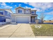 Two-story house with gray siding, attached garage, and landscaped front yard at 5399 Walden Ct, Denver, CO 80249