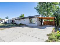 Ranch style home with carport, landscaping, and paved driveway at 1626 S Sheridan Blvd, Denver, CO 80232