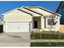 Attractive light beige exterior of a ranch style home with a two-car garage at 870 Sawdust Dr, Brighton, CO 80601