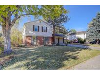 Brick ranch house with a spacious lawn, mature trees, and a two-car garage at 6867 S Elizabeth St, Centennial, CO 80122