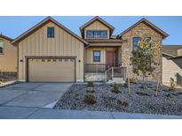 Beige two-story house with stone accents and a two-car garage at 665 Scrubjay Cir, Castle Rock, CO 80104