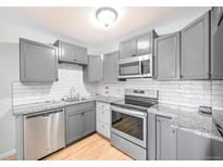 Modern kitchen with gray cabinets, granite countertops, and stainless steel appliances at 9340 E Center Ave # 8B, Denver, CO 80247