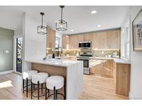 Modern kitchen featuring light wood cabinets, stainless steel appliances, and an island with seating at 2650 S Lafayette St, Denver, CO 80210