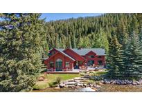Aerial view of a red house near a river with a mountain backdrop at 189 Ginger Quill Ln, Breckenridge, CO 80424