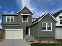 Two-story craftsman style home with gray siding, white garage door, and landscaping at 16653 W 93Rd Way, Arvada, CO 80007