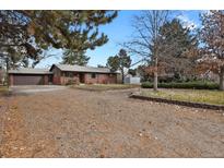 Brick ranch home with a gravel driveway and mature trees at 1760 S Uinta Way, Denver, CO 80231