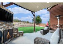 Relaxing patio with fireplace, artificial turf, and backyard views at 3745 Spanish Oaks Trl, Castle Rock, CO 80108