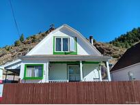 Charming white house with green accents and a mountain view at 902 Virginia St, Idaho Springs, CO 80452