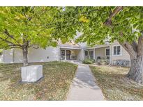 Tan siding condo building with walkway, landscaping, and a tree with fall leaves at 2604 S Xanadu Way # B, Aurora, CO 80014