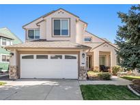 Two-story house with beige siding, white garage door, and landscaping at 180 Peregrine Cir, Broomfield, CO 80020