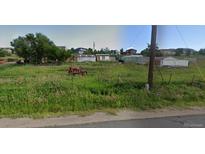 Vacant lot with overgrown grass, a rusty tractor, and neighboring houses in the background at 13305 W 82Nd Ave, Arvada, CO 80005