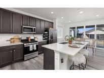 Modern kitchen with dark cabinetry, island, and stainless steel appliances at 3989 Gold Bug St, Aurora, CO 80019