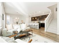 Open concept living room with kitchen, island, and stairs at 6041 N Orleans St, Aurora, CO 80019