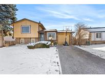 Ranch style home with a snow covered driveway and basketball hoop at 18936 E Colorado Dr, Aurora, CO 80017