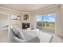 Bright living room with fireplace and sliding glass doors leading to a balcony at 1801 S Dunkirk St # 303, Aurora, CO 80017