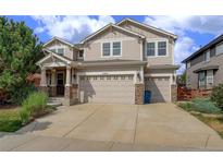 Two-story house with beige siding, a three-car garage, and landscaping at 15453 E 109Th Ave, Commerce City, CO 80022