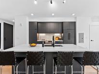 Modern kitchen with dark cabinetry, a large island, and stainless steel appliances at 1601 Park Ave # 212, Denver, CO 80218