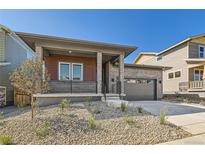 Modern two-story home with a covered porch, attached garage, and landscaped yard at 2700 E 102Nd Pl, Denver, CO 80229