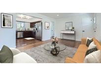Open living room with kitchen view and hardwood floors at 6335 Martin Luther King Jr Blvd, Denver, CO 80207