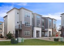 Modern three-story townhome with brick and gray siding at 455 Interlocken Blvd # 102, Broomfield, CO 80021
