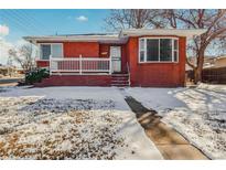 Brick ranch home with a covered porch and snowy lawn at 2200 W Moffat Pl, Denver, CO 80221
