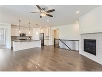 Open living room with fireplace, hardwood floors, and kitchen island at 2385 Provenance St, Longmont, CO 80504