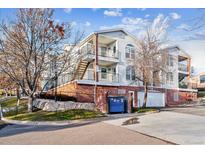 View of the exterior of a light-colored condo building with balconies and a dumpster in front at 1648 S Cole St # B7, Lakewood, CO 80228