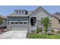 Two-story craftsman style home with gray siding, stone accents, and a two-car garage at 8901 S Ukraine Ct, Aurora, CO 80016