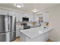 Modern kitchen boasts white cabinets, stainless steel appliances, and a large island at 14585 W 32Nd Ave, Golden, CO 80401