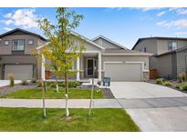 Two-story home with gray siding, a front porch, and a two-car garage at 13351 E 100Th Pl, Commerce City, CO 80022