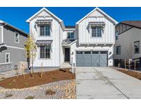 Two-story farmhouse style home with gray garage doors at 8856 Snake River St, Littleton, CO 80125