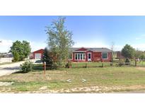 Ranch style home with red exterior, large yard, and a swing set at 16163 Barley Ave, Fort Lupton, CO 80621