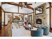 Spacious living room with exposed beams, stone fireplace, and hardwood floors at 22759 Mountain Spirit Way, Indian Hills, CO 80454
