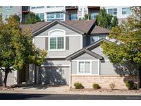 Townhouse exterior view with gray siding, brick accents, and a two-car garage at 1355 S Ulster St, Denver, CO 80231